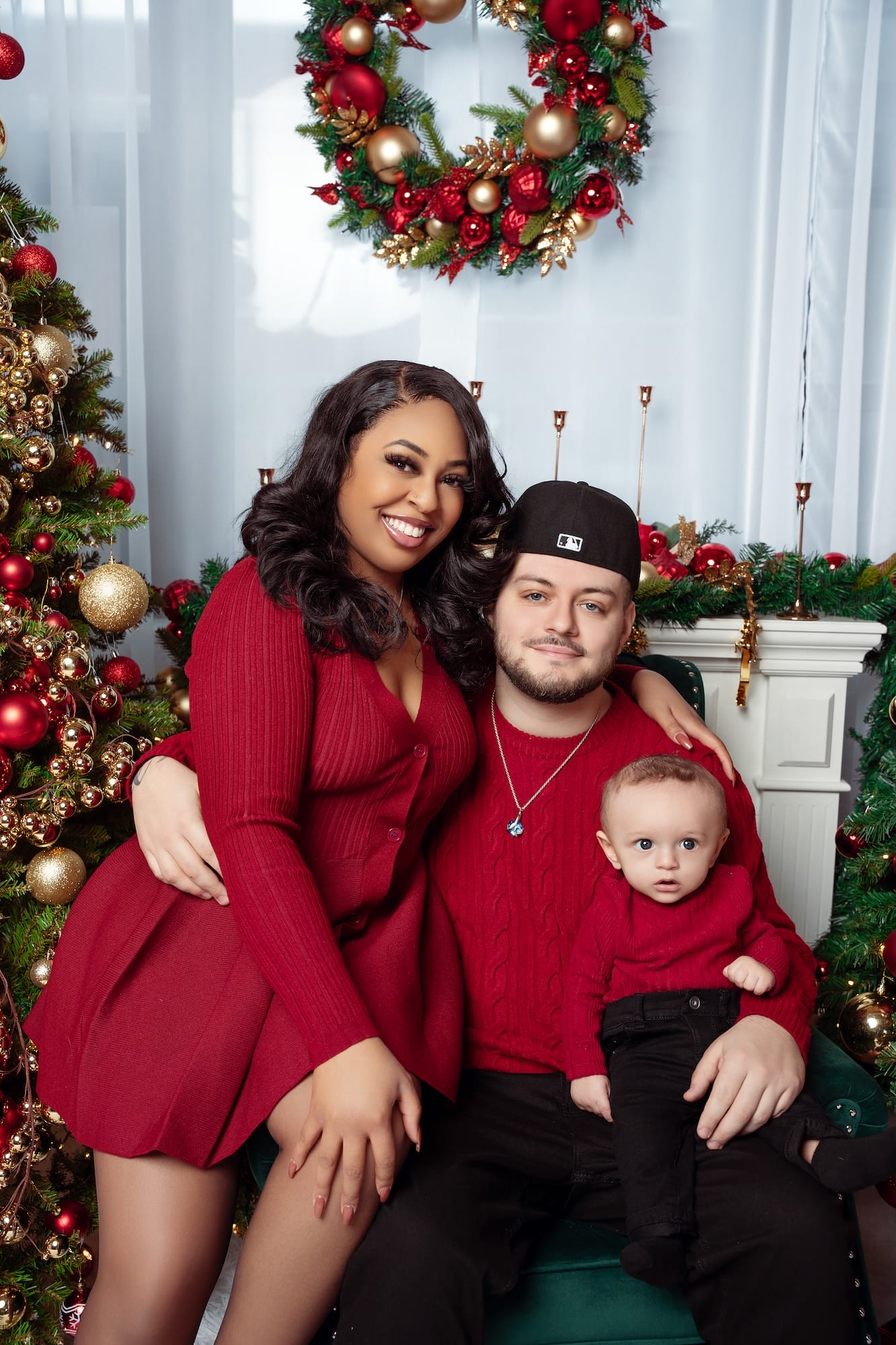 Family in red sweaters posing by a Christmas fireplace