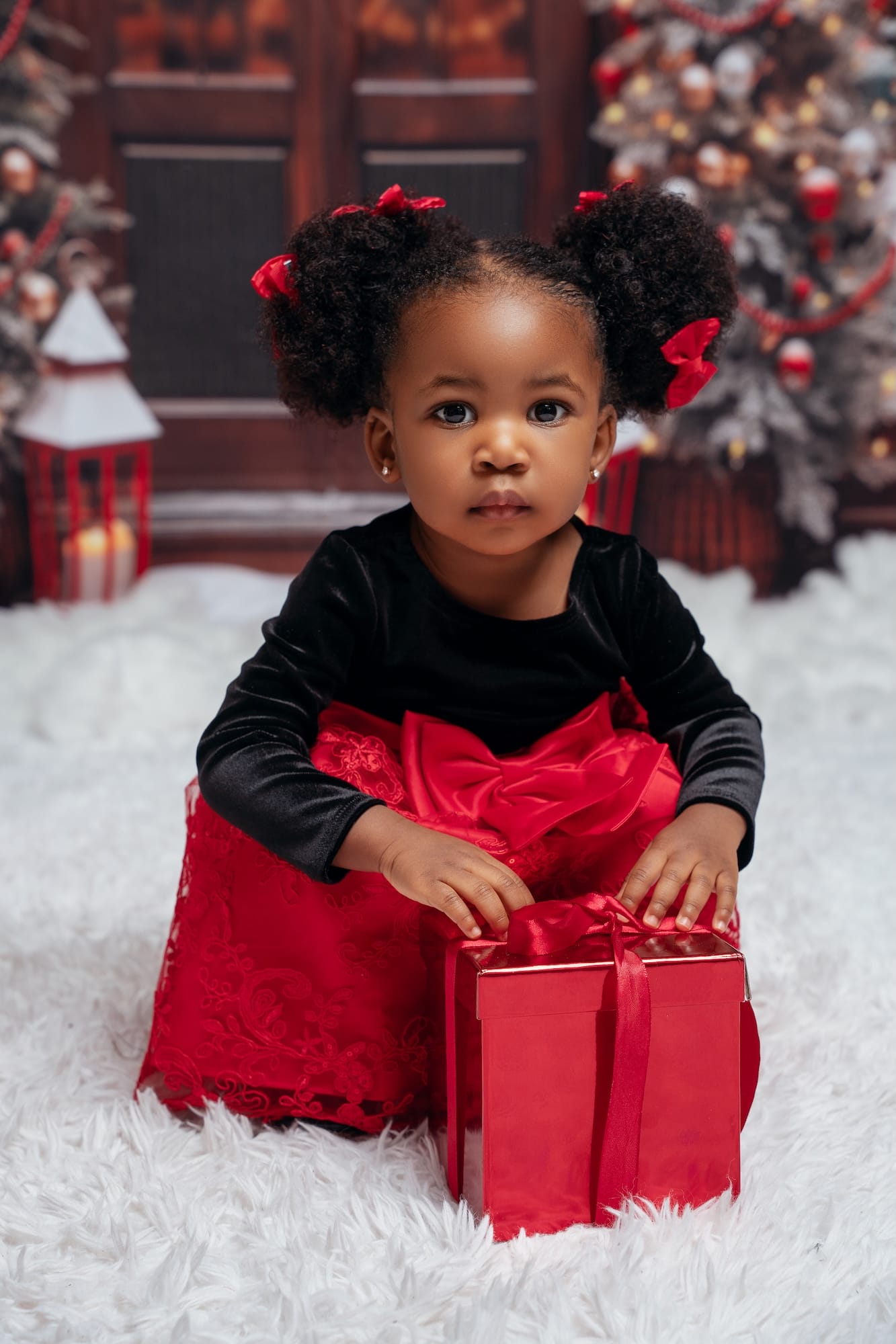 Girl holding a Christmas gift beside a decorated tree